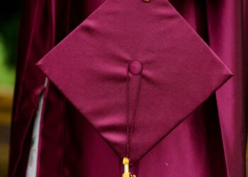 woman holding purple mortar board wearing toga
