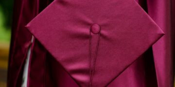 woman holding purple mortar board wearing toga