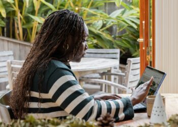a person standing in front of a laptop computer talking on a cell phone