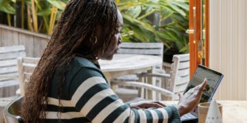 a person standing in front of a laptop computer talking on a cell phone